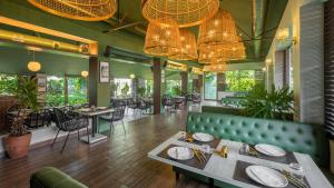 restauracja z zieloną kanapą, stołami i krzesłami w obiekcie Green Meadows Resort w mieście Ćennaj