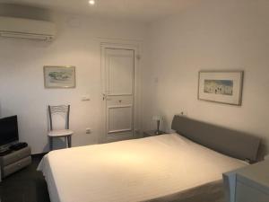 a bedroom with a white bed and a chair at La Sirena in Les tres Cales