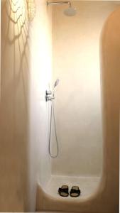 a bathroom with a shower with a pair of slippers at The Nine Graces - Beach Apartment Clea, hot tub and sea views in Agia Anna Naxos +31 photos