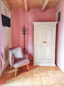 Cette chambre rose comprend une chaise et une armoire blanche. dans l'établissement Rocca dell'Innominato, à Lecco