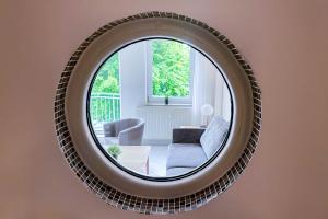 un miroir reflétant un salon avec une chaise et un canapé dans l'établissement FEWO Ava - im Sommer ist ein Strandkorb inclusive, à Zempin