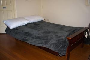 a bed with a black blanket on a wooden floor at Orana"Welcome" Cabin in The Tops in Bandon Grove