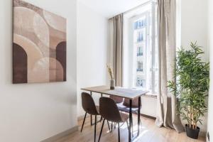 a dining room with a table and chairs and a window at HSH Volney-Opéra Appartement Design 4P-1BR in Paris