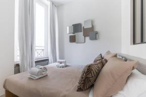 Un dormitorio blanco con una cama con toallas. en HSH Volney-Opéra Appartement Design 4P-1BR, en París