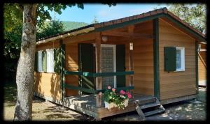 a small cabin with a porch and a tree at Chalet Beau Rivage in Gunsbach