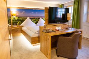 een kamer met een bureau, een televisie en een bed bij Gasthaus Winzerstube & Hotel in Rödelsee