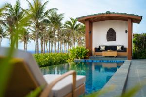 una villa con piscina y palmeras en Mövenpick Resort Cam Ranh, en Cam Ranh