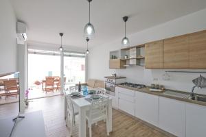 una cocina con armarios blancos y una mesa. en Appartamento Fiordaliso, en Leuca