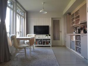 sala de estar con mesa, sillas y TV en Cosy modern apartment with lagoon view, en Preila