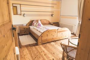 um quarto com uma cama de madeira e um piso de madeira em Wein & Gästehof Erlacher em Hartmannsdorf