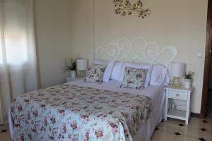 1 dormitorio con cama con colcha y almohadas de flores en Apartamentos Oncemolinos con desayuno en Consuegra