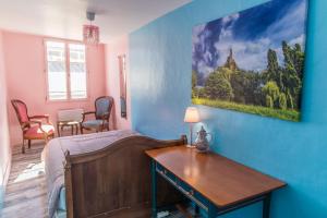 勒布伊Garage, 2 chambres, balnéo, 2 SDB, 2WC, vue sur les monuments的卧室配有一张床和一张桌子,墙上挂有绘画作品