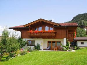 ein Haus mit einem Balkon mit roten Blumen darauf in der Unterkunft Landhaus Mitteregger in Kaprun