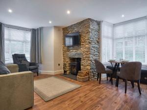 a living room with a stone fireplace and a table and chairs at Lower Sheriff's Place in Windermere