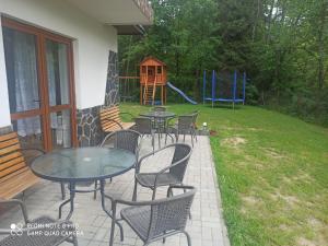 een patio met tafels en stoelen en een speeltuin bij Helena Gał in Białka Tatrzanska