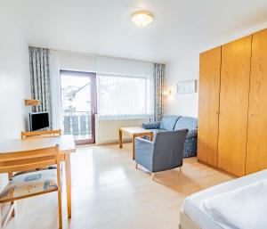 ein Wohnzimmer mit einem Bett, einem Schreibtisch und einem Sofa in der Unterkunft Aparthotel Panorama in Bad Soden-Salmünster