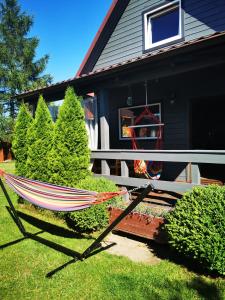 a hammock sitting in the grass in front of a house at Stilove Wydmy in Sasino