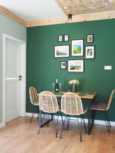 Apartament MONTANA في كارباش: غرفة طعام بجدار أخضر مع طاولة وكراسي
