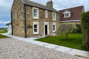 a stone house with a grass yard in front of it at Castle View House in Dalkeith