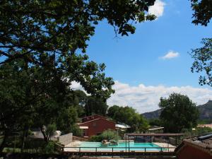 a swimming pool in a yard with a red house and trees at camping mas du sartre in Auriolles