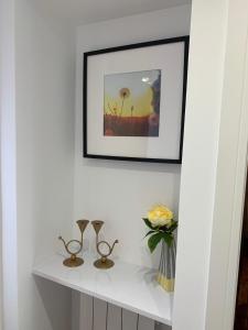 a white shelf with a picture and a vase of flowers at Causewayside in Edinburgh