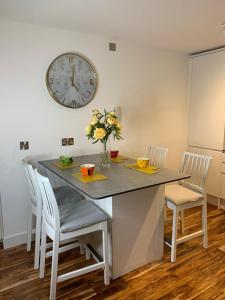 a dining room table with chairs and a clock on the wall at Causewayside in Edinburgh