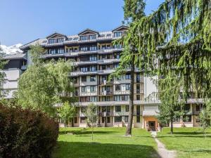 um grande edifício de apartamentos com um parque em frente em Appartement Cosy - Aiguille du Midi em Chamonix-Mont-Blanc