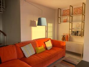 pomarańczowa kanapa z poduszkami w salonie w obiekcie Tres Terrazas Ocean view apartment w Adeje