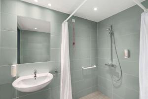 
a bathroom with a shower, sink, and toilet at Super 8 by Wyndham Munich City West in Munich
