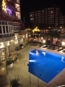 una gran piscina azul en una ciudad por la noche en Ohtels Gran Hotel Almeria, en Almería