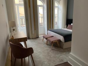a bedroom with a bed and two chairs and windows at Pharmacia GuestHouse in Coimbra