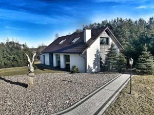 mały biały dom z posągiem przed nim w obiekcie Domek Kaszuby Sominy Luxhut w mieście Sominy