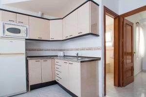 a kitchen with white cabinets and a sink and a microwave at APARTAMENTOS CARMEN in Maro