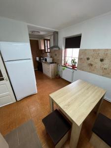 a kitchen with a wooden table and a white refrigerator at Villa Dumbrava Rosie in Constanţa