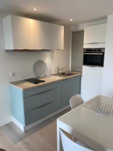a kitchen with white cabinets and a sink and a table at Roi Soleil in Le Touquet-Paris-Plage