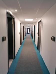 a corridor of a hallway with a blue carpet at Kyriad Direct Orleans - Olivet - La Source in Olivet