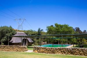 a swimming pool with a stone wall next to a building at Steenbok farm cottages Aalwyn Cottage in Wolseley