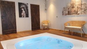 een groot blauw bad in een kamer met 2 stoelen bij Etangs du Moulin in Suzy