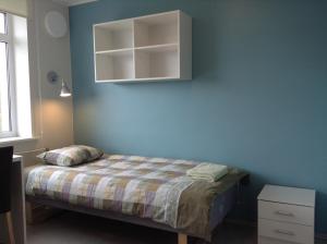1 dormitorio con cama y pared azul en Hiiumaa Ametikooli Accommodation, en Suuremõisa