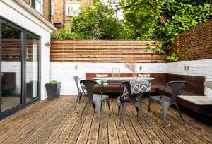 a patio with a table and chairs on a deck at The Heart of Shepherds Bush - Modern 2BDR Apartment with Garden in London