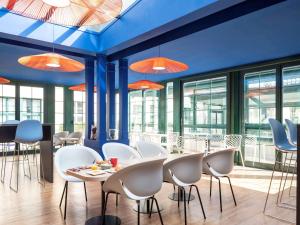 a restaurant with white chairs and tables and windows at Aparthotel Adagio Val d'Europe près de Disneyland Paris in Serris