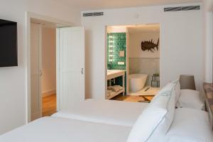 a bedroom with a white bed and a bathroom at Hotel Fariones in Puerto del Carmen