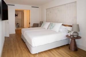 a bedroom with a large white bed and a table at Hotel Fariones in Puerto del Carmen
