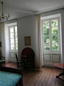 Cette chambre comprend un lit, deux fenêtres et une table. dans l'établissement MAISON ALBA LA SOURCE, à Mazamet