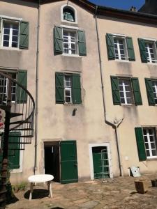 un bâtiment avec des volets verts et une table en face dans l'établissement MAISON ALBA LA SOURCE, à Mazamet