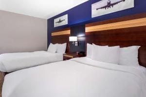 
a hotel room with two beds and two lamps at Avion Inn Near LGA Airport, Ascend Hotel Collection in Queens

