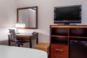 
a hotel room with a television and a chair at Avion Inn Near LGA Airport, Ascend Hotel Collection in Queens
