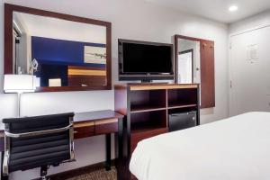 a bedroom with a bed and a desk with a television at Avion Inn Near LGA Airport, Ascend Hotel Collection in Queens