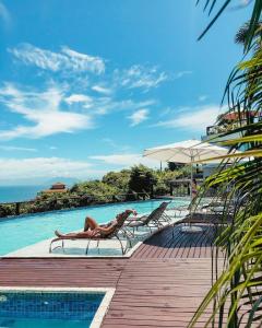 a woman laying on a chair next to a swimming pool at Eny Boutique Hotel & Spa in Búzios