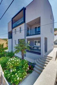 ein weißes Haus mit einer Palme davor in der Unterkunft Apartments Hemetek in Veli Lošinj